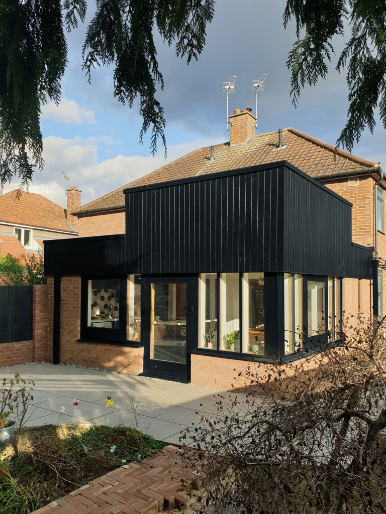 A self-build house extension with black timber cladding and brick.